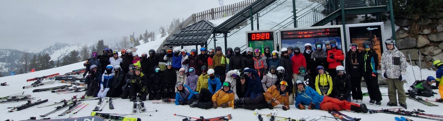 Skupina lyžařů a snowboardistů před horskou stanicí lanovky